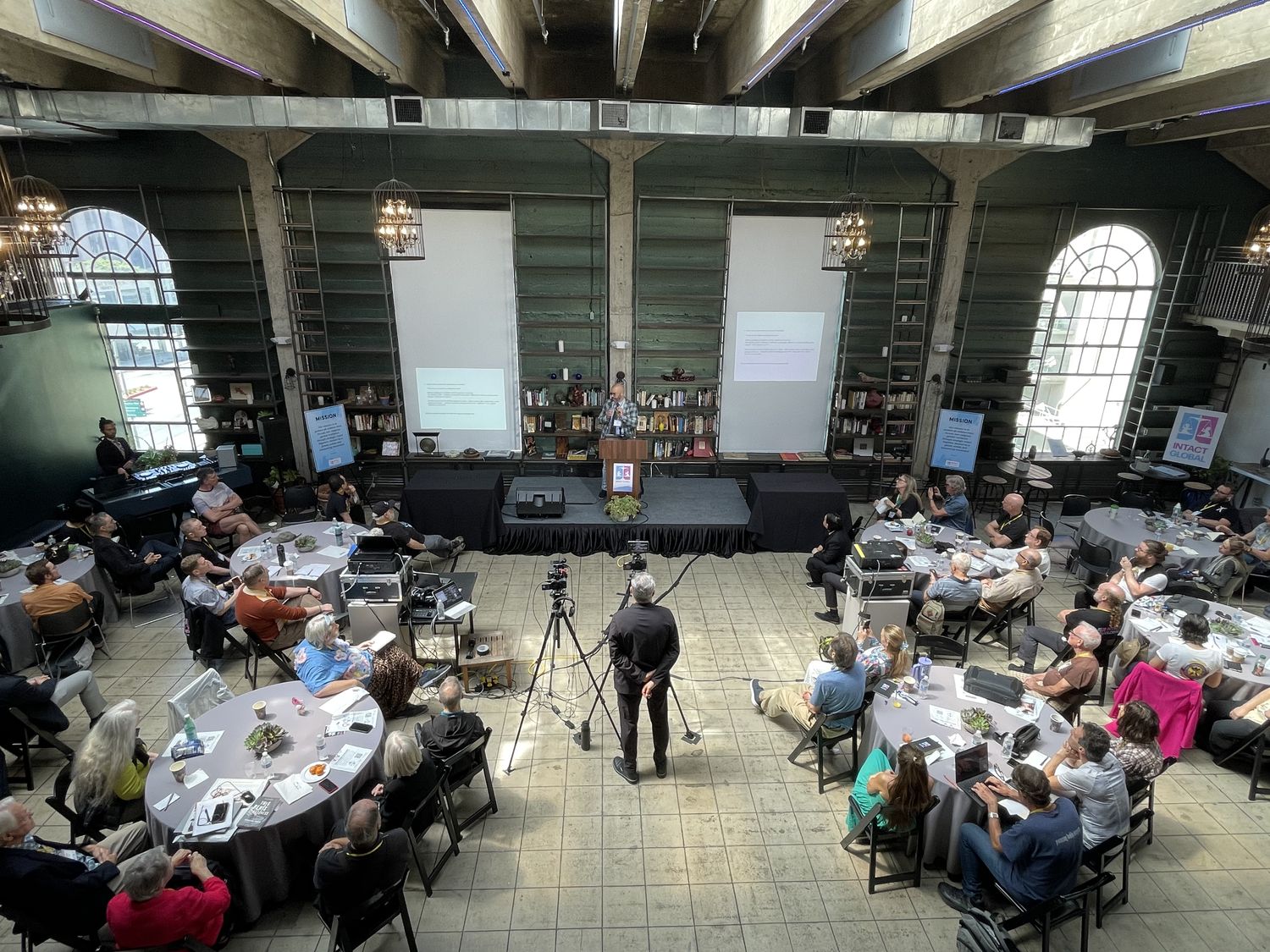Historic Dancehall configured for a conference with round tables, stage, and chandeliers