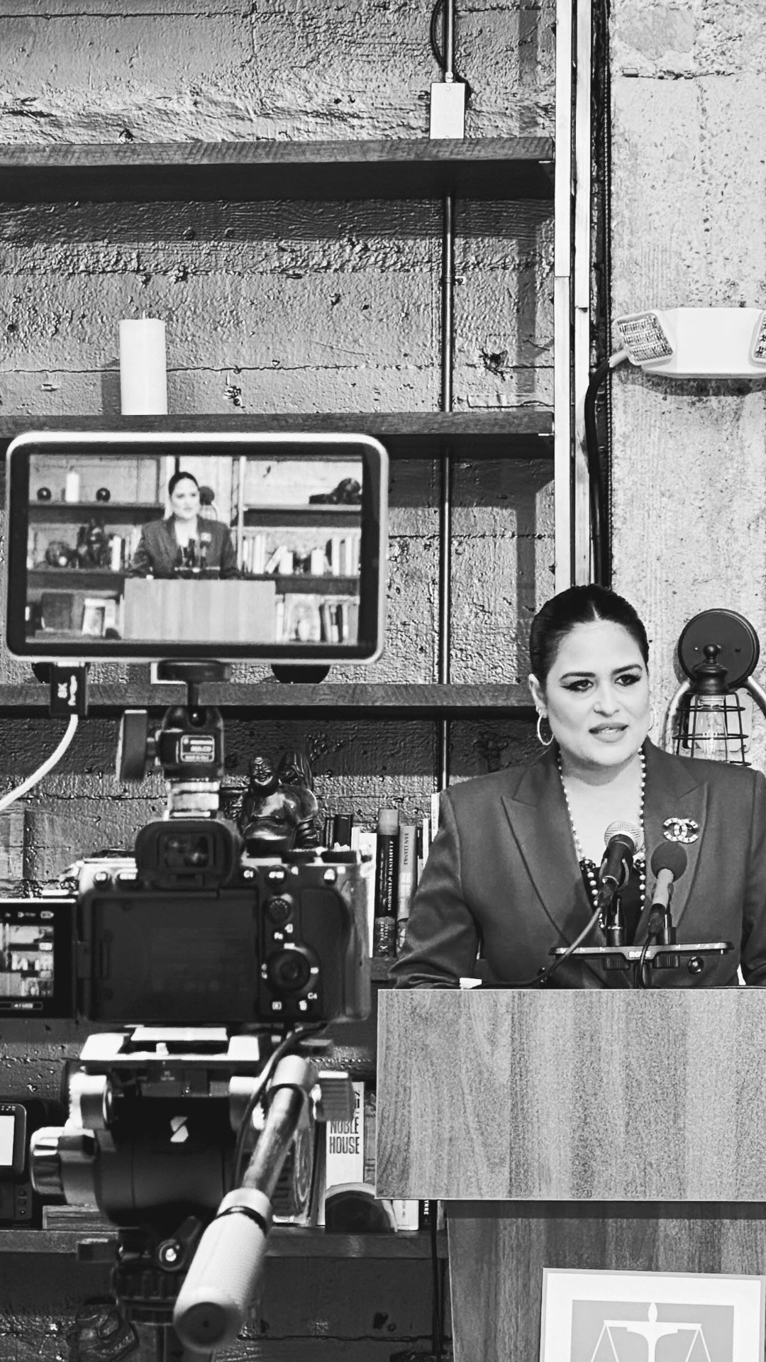 Camera filming a conference speaker at a podium inside Historic Dancehall